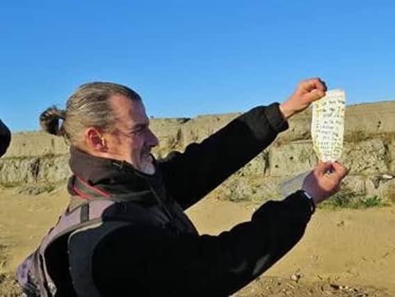 Stuart Thompson holding the message in a bottle found on the beach.