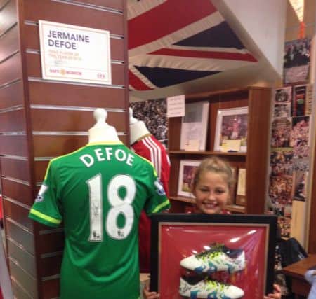 Angel Herd alongside a match-worn Jermain Defoe shirt, and holding the boots he scored in against Chelsea last season.