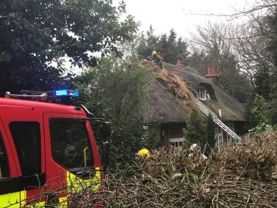 Firefighters dealing with a thatched roof on fire.