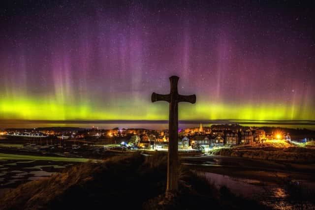 The Northern Lights over Alnmouth in Northumberland at the St Cuthbert's Cross, which is said to be the location where St Cuthbert agreed to become Bishop of Lindisfarne. Pic: Owen Humphreys/PA Wire.