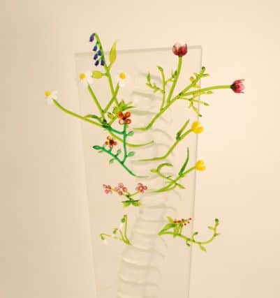 A glasswork piece by Gary Nicholson, which combines colourful flowers with a transparent spine.