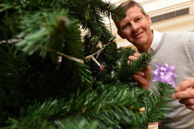 Steve Cram hangs the first bauble on the St Benedict's Hospice charity tree.
