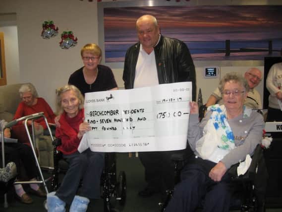 Thomas Corkhill hands a cheque for Â£750 over to Beachcomber Care Home manager Julie Cole and residents of the home.