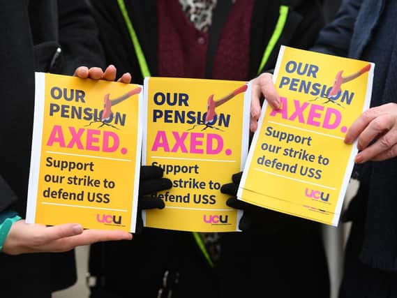 University workers hold leaflets they begin a month of walkouts in the latest stage of a bitter dispute over pensions. Pic: PA.