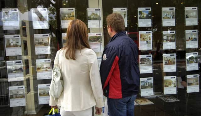 A couple outside an estate agent's window.