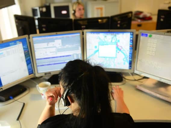 A police call handler takes reports in a force control room.