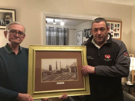 Peter Shields and Coun Phil Tye with a picture of the Silksworth pit wheel.