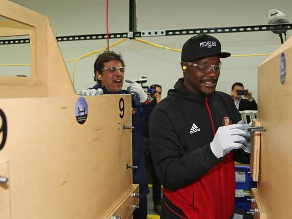 Lamine Kone and Chris Coleman work on a simulated work experience machine at the Caterpillar plant.