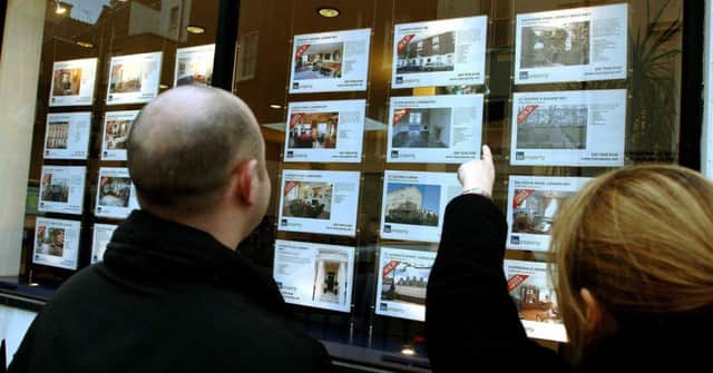 A young couple studying property for sale in an estate agent's window.