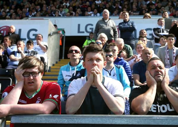 Swansea fans looking dejected during the Premier League match at the Liberty Stadium, Swansea. PRESS ASSOCIATION Photo. Picture date: Sunday May 13, 2018. See PA story SOCCER Swansea. Photo credit should read: David Davies/PA Wire. RESTRICTIONS: EDITORIAL USE ONLY No use with unauthorised audio, video, data, fixture lists, club/league logos or "live" services. Online in-match use limited to 75 images, no video emulation. No use in betting, games or single club/league/player publications.